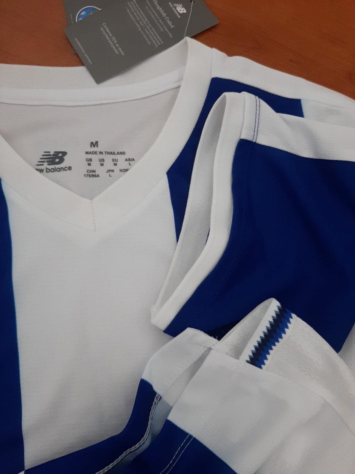 Detalhe aproximado dos acabamentos elásticos premium nas mangas e gola em V da camisola principal do FC Porto 26/27