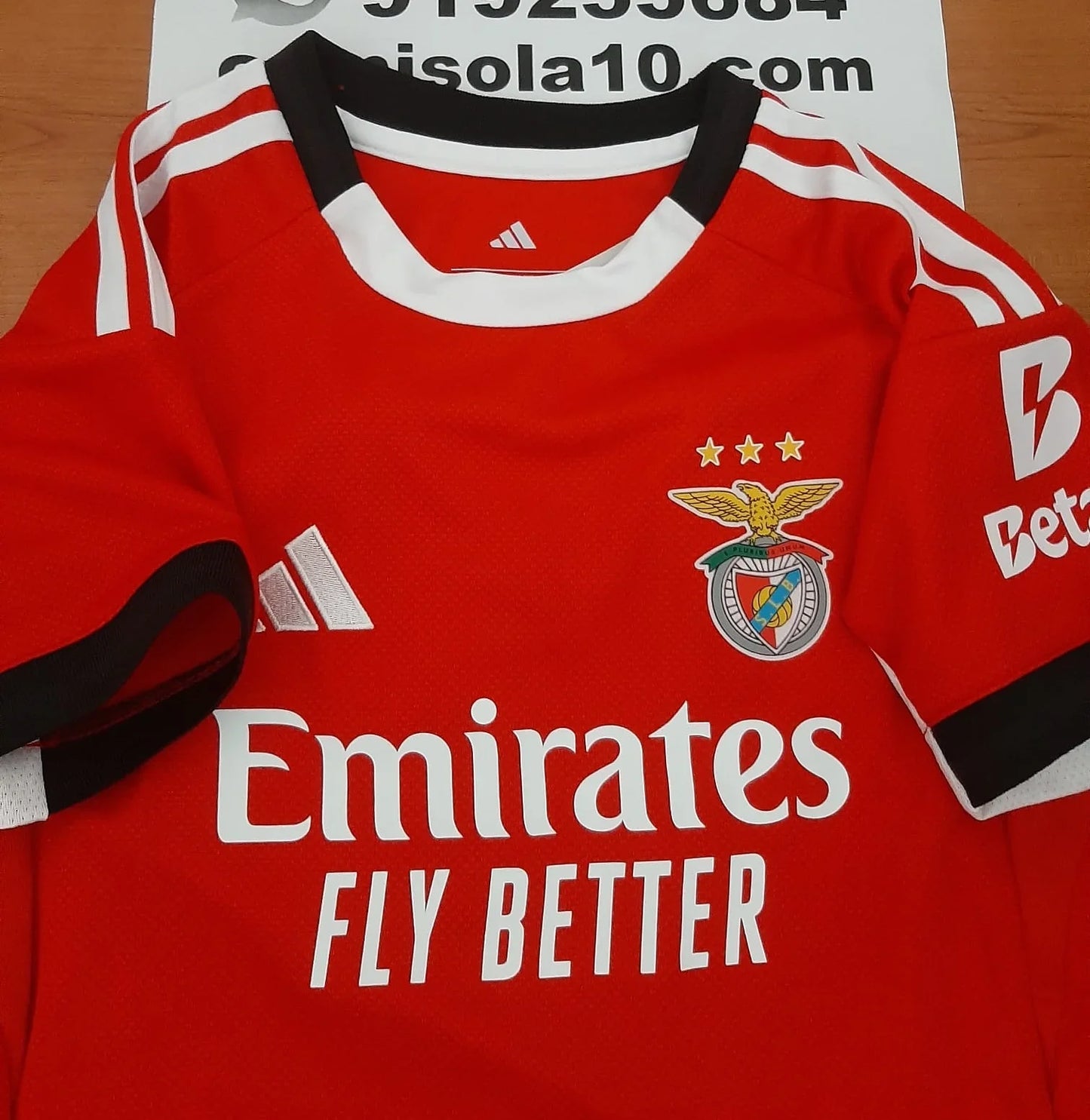 Pormenor do emblema do SL Benfica e logótipo na camisola de criança 25/26.