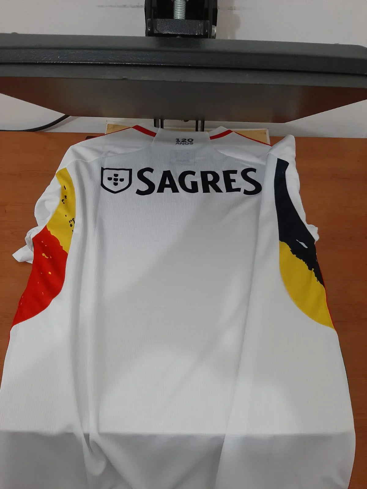 Vista das costas da camisola do Benfica 23/24 com o patrocínio Sagres e detalhes coloridos.