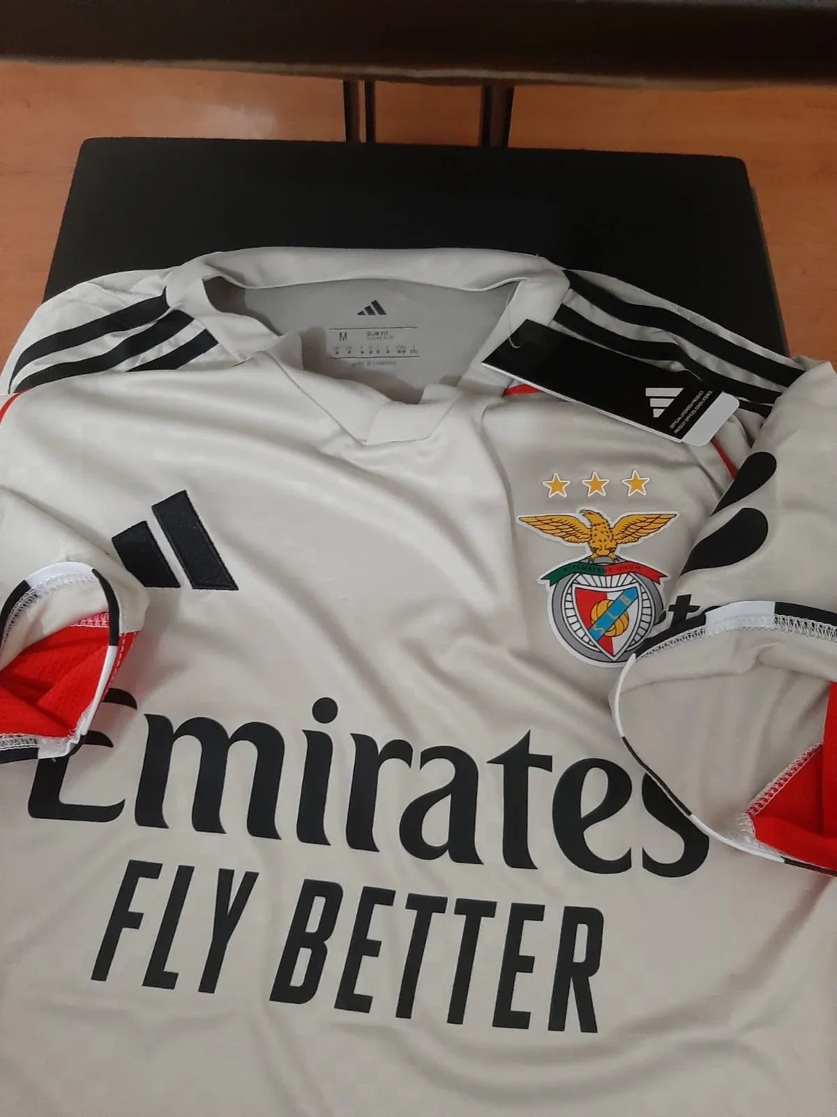 Camisola principal SL Benfica 25/26 bege, vista frontal com patrocínio Emirates Fly Better, tamanho M