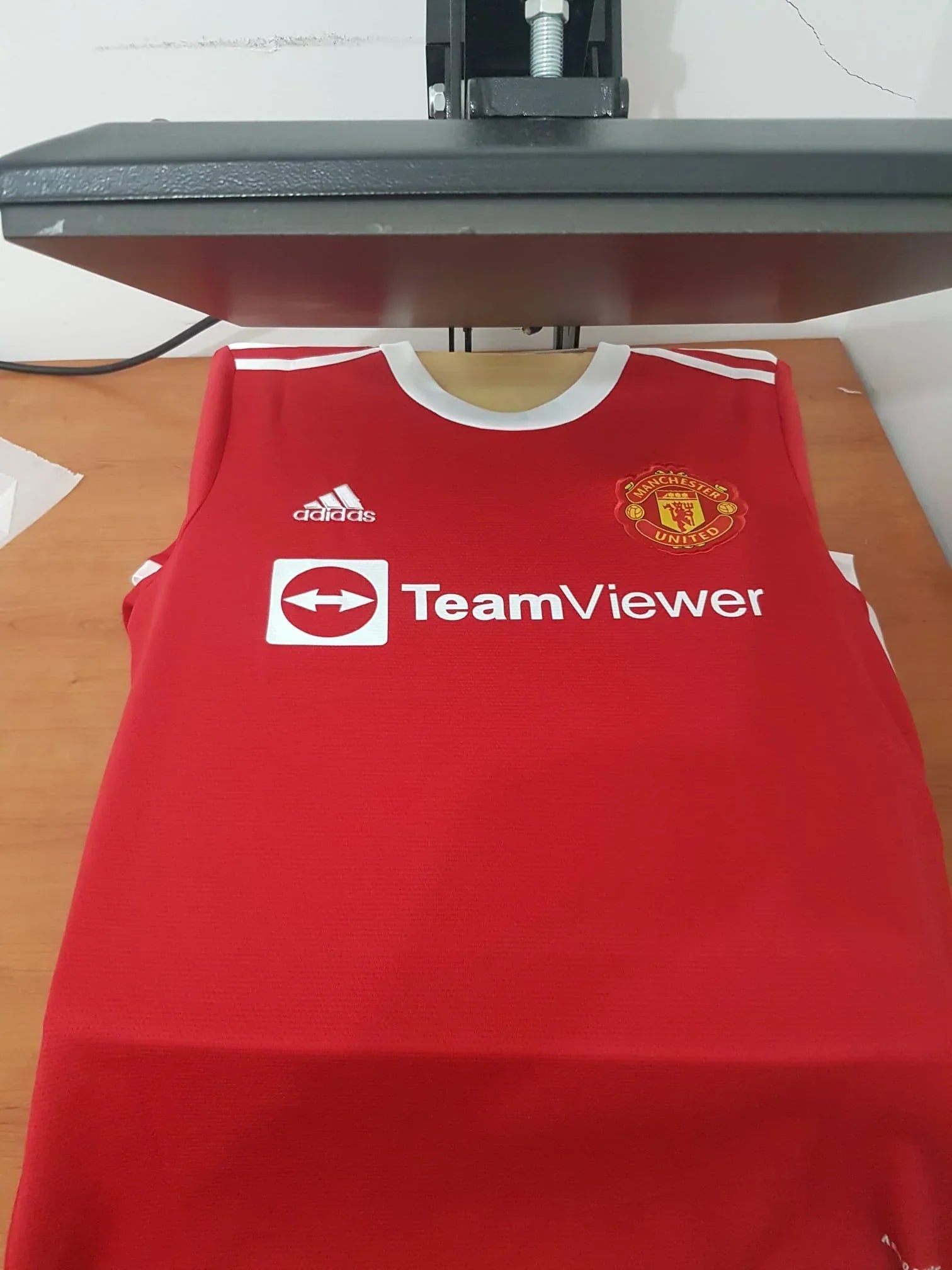 Frente da camisola do Manchester United 21/22 com patrocínio TeamViewer na prensa de estampagem.