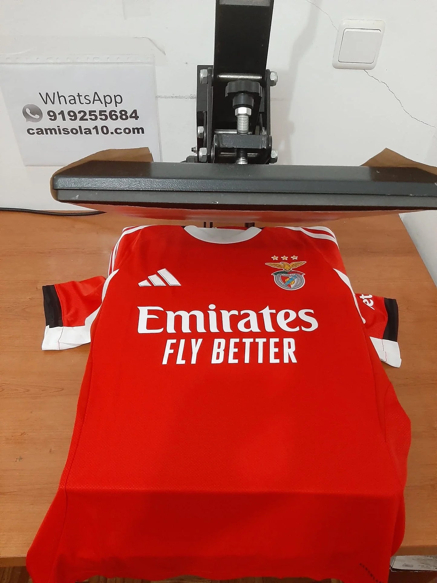 Vista frontal da camisola principal do SL Benfica 25/26 na prensa de personalização da Camisola10 