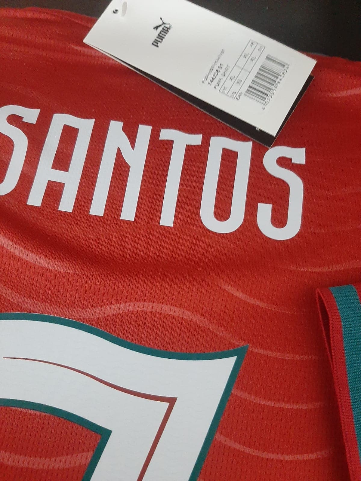 Detalhe aproximado dos acabamentos e costuras da camisola de Portugal com a estampagem personalizada do nome Santos e número 7