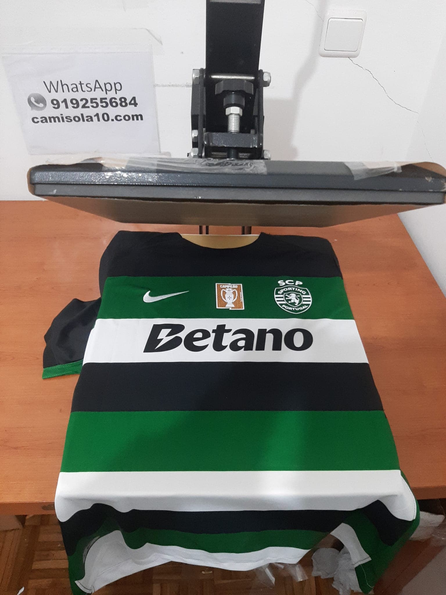 T-shirt comemorativa da Dobradinha do Sporting CP, tamanho M, com detalhes dos troféus do Campeonato e Taça de Portugal. Vista frontal