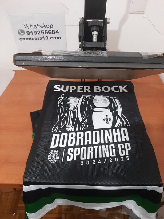 Camisola comemorativa da Dobradinha do Sporting CP, tamanho M, com detalhes dos troféus do Campeonato e Taça de Portugal.