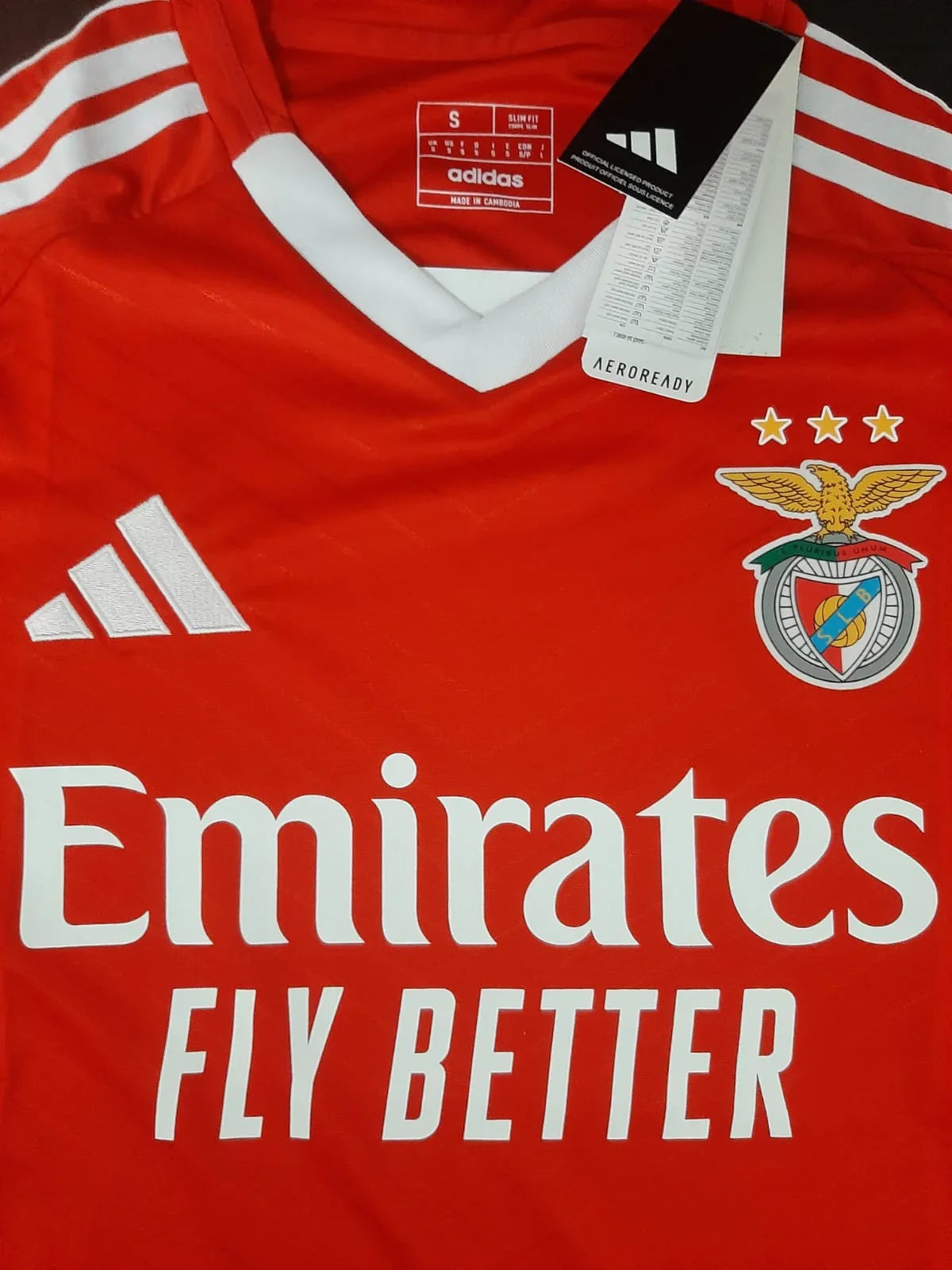Pormenor do emblema do SL Benfica e logótipo do patrocinador Emirates na camisola principal 24/25.