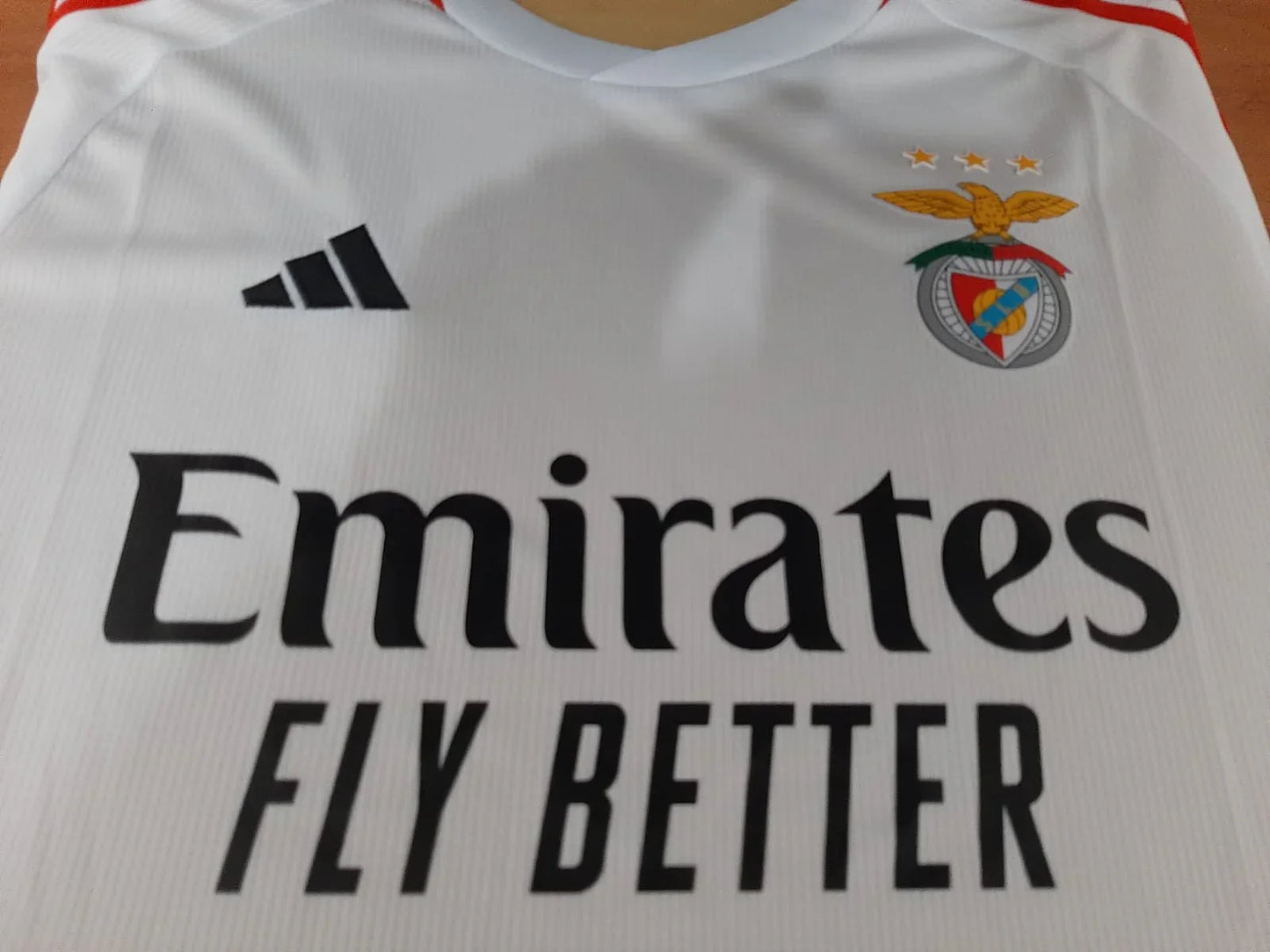 Close-up do emblema do SL Benfica,  patrocinador Emirates na camisola branca.