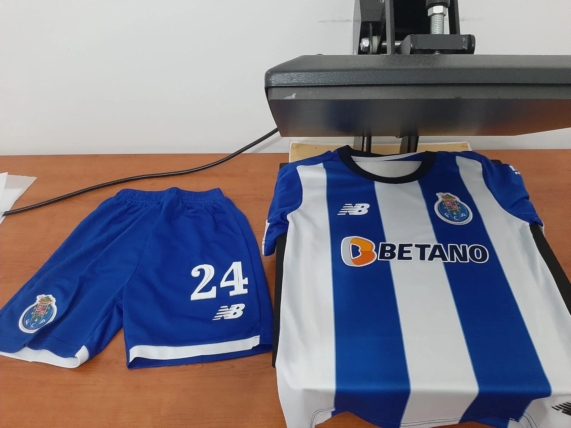 Conjunto completo de criança (camisola e calções) do FC Porto época 23/24 na prensa de estampagem