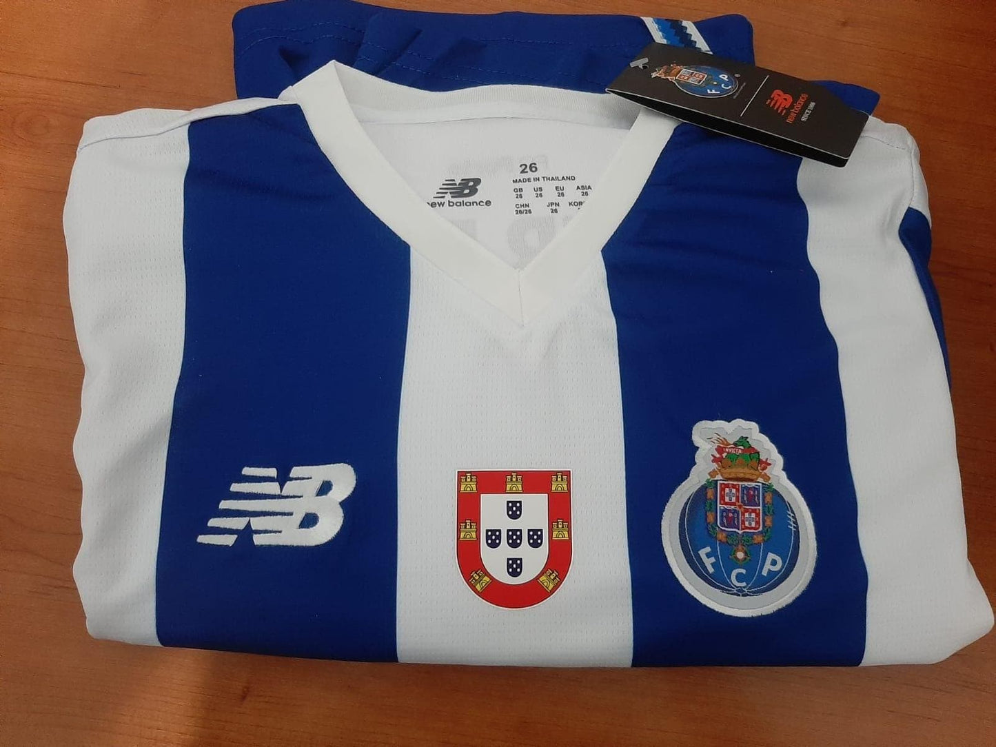 Detalhe frontal da camisola principal de criança do FC Porto 26/27 com o escudo de Campeão das quinas e emblema do clube 