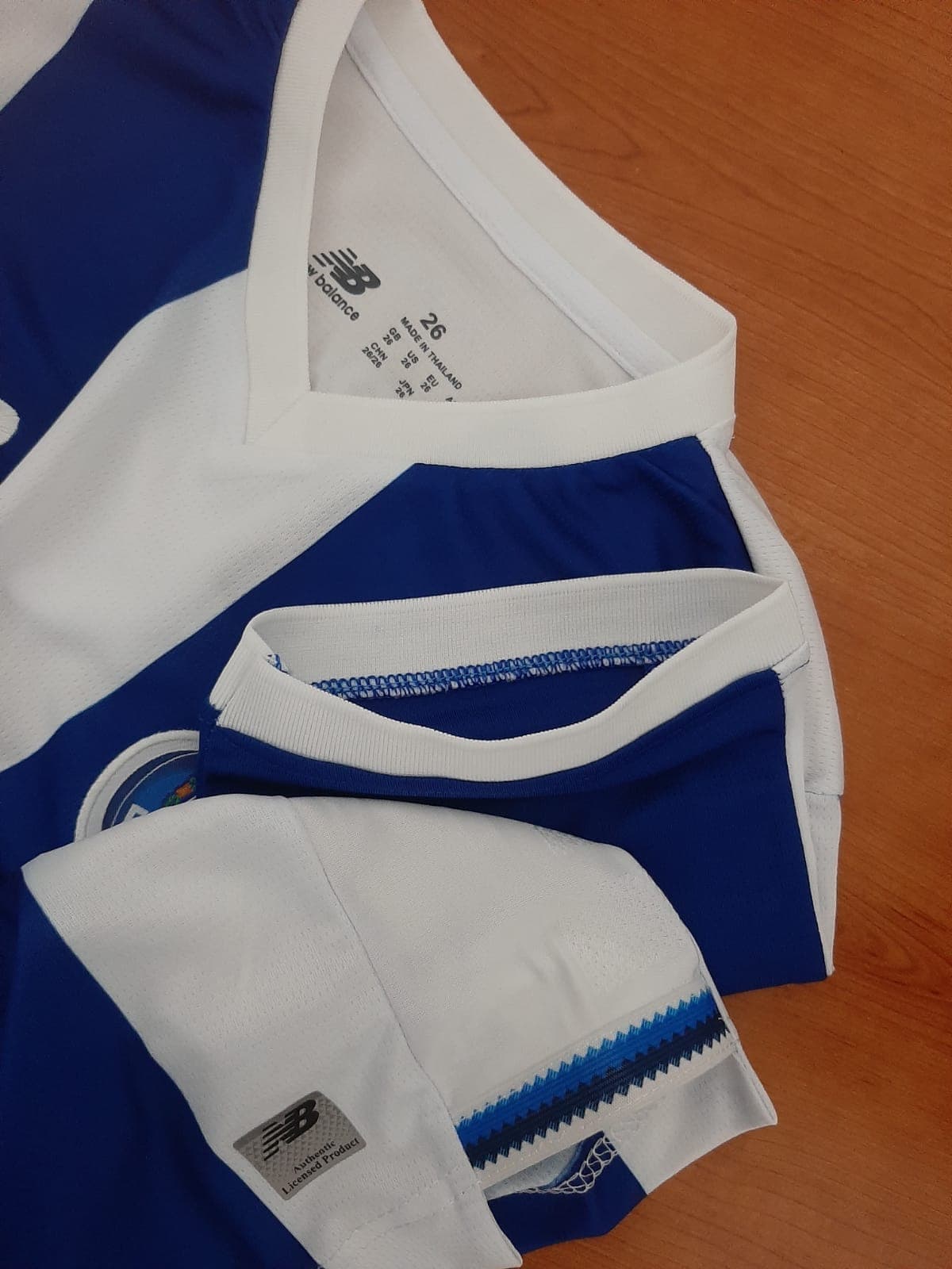 Pormenor dos acabamentos com elástico de alta qualidade nas mangas e gola da camisola de criança do FC Porto 26/27