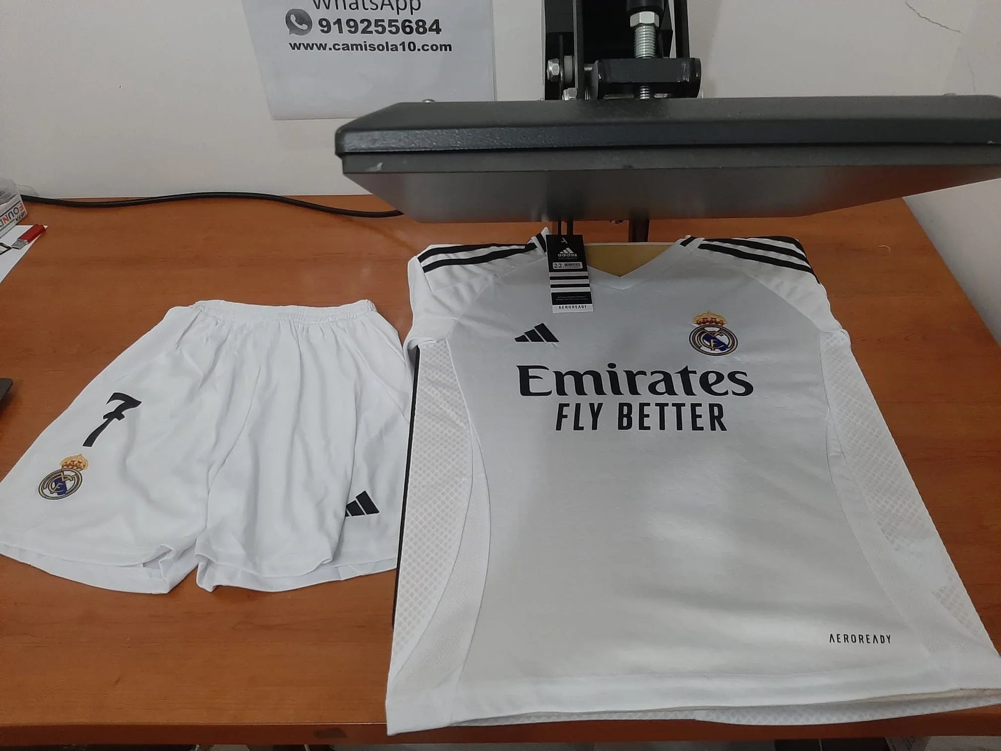 Kit de criança principal (camisola e calções) do Real Madrid 24/25 na prensa de estampagem.