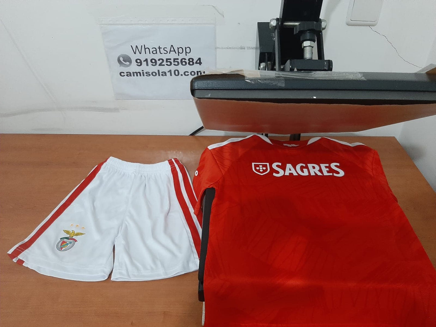 Costas do kit de criança do SL Benfica 26/27 com o patrocínio Sagres na camisola e calções brancos de jogo